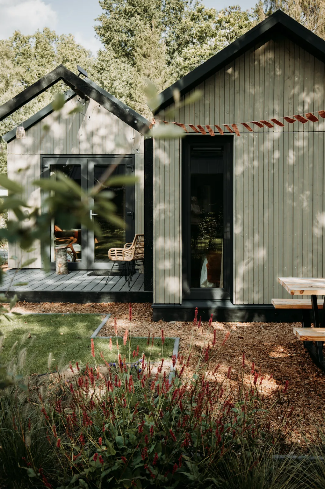Tiny house Hjort van buiten met veranda en slinger, tussen het groen op de Veluwe