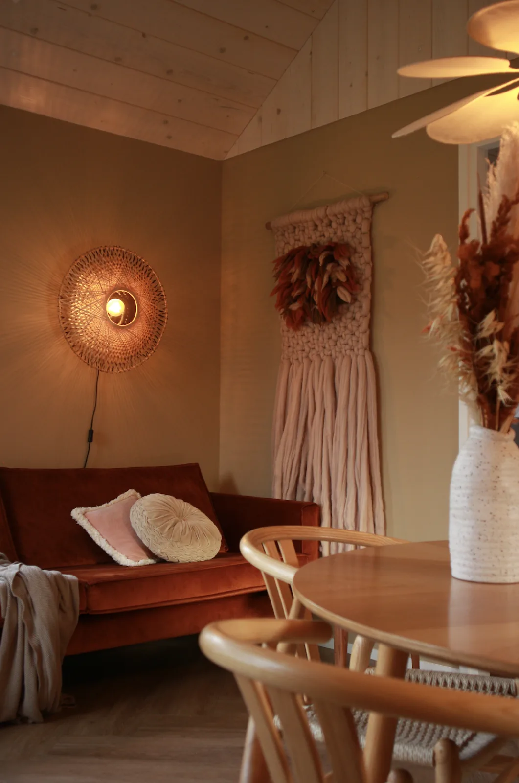 De woonkamer van tiny house Hjort met de roestbruine bank en warm lamplicht